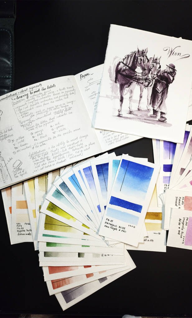 Overhead view of Aliya Bodnar’s watercolour sketches and colour palette studies laid out on textured paper in her studio