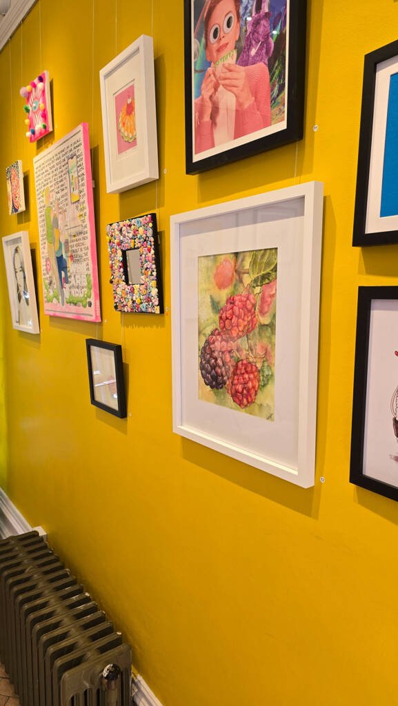 Aliya Bodnar’s painting “Blackberries from the Garden” displayed on a bright yellow wall during the TASTE group exhibition in Medway, 2025