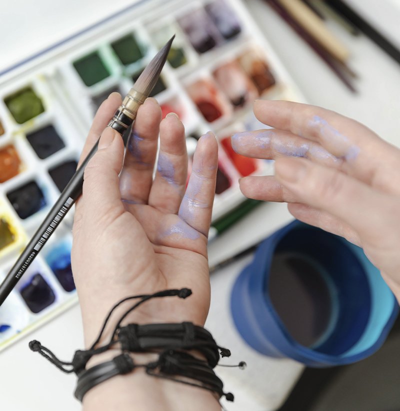 Close-up of Aliya Bodnar’s hands mixing watercolor paints in her studio.