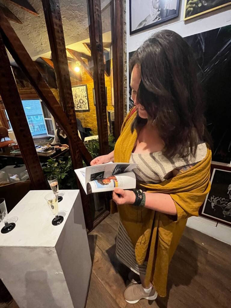 Aliya Bodnar signing the official exhibition catalog at Boomer Gallery during The Vogue Seventh Edition Exhibition in London.