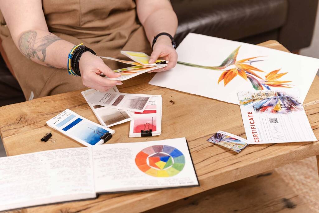 Watercolour artist Aliya Bodnar painting in her studio, surrounded by creative tools and finished artworks