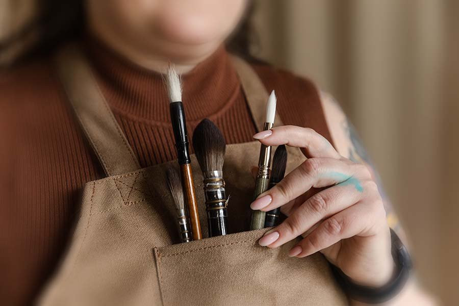 Aliya Bodnar holding paintbrushes, close-up of hands showing her creative process as a watercolour artist in the UK