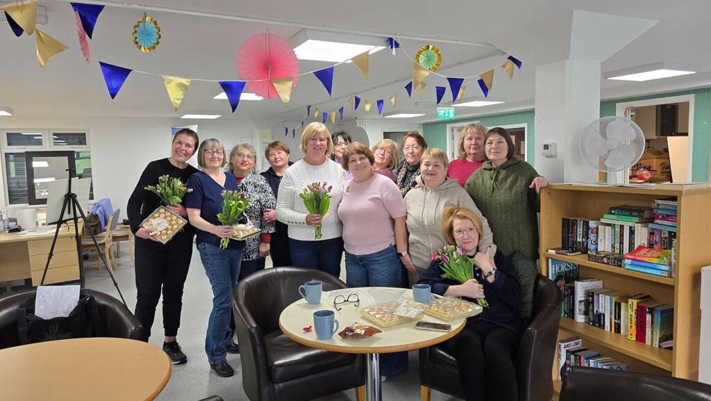 Participants celebrating the end of Aliya Bodnar’s sunflower watercolor workshop in a festive, decorated classroom.