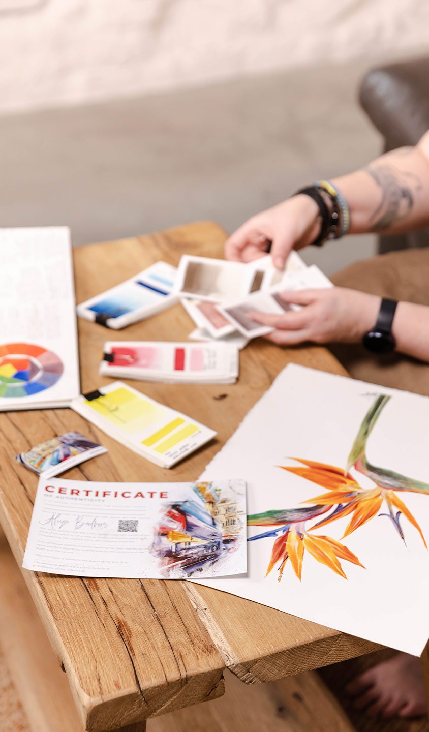 Close-up of Aliya Bodnar’s hands preparing her watercolour palette in the studio, surrounded by art materials