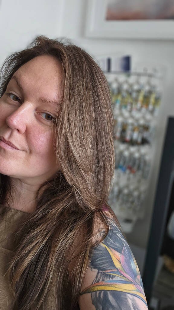Aliya Bodnar smiling in her home studio, radiating warmth and creative joy.