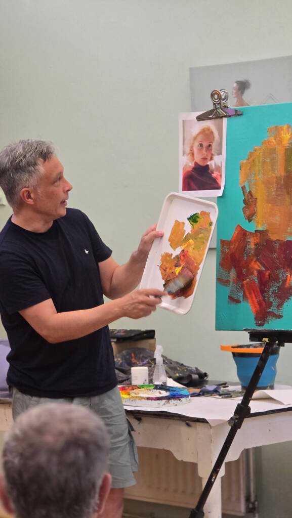An art instructor demonstrates a technique to participants during a live workshop at Rochester & West Kent Art Society.