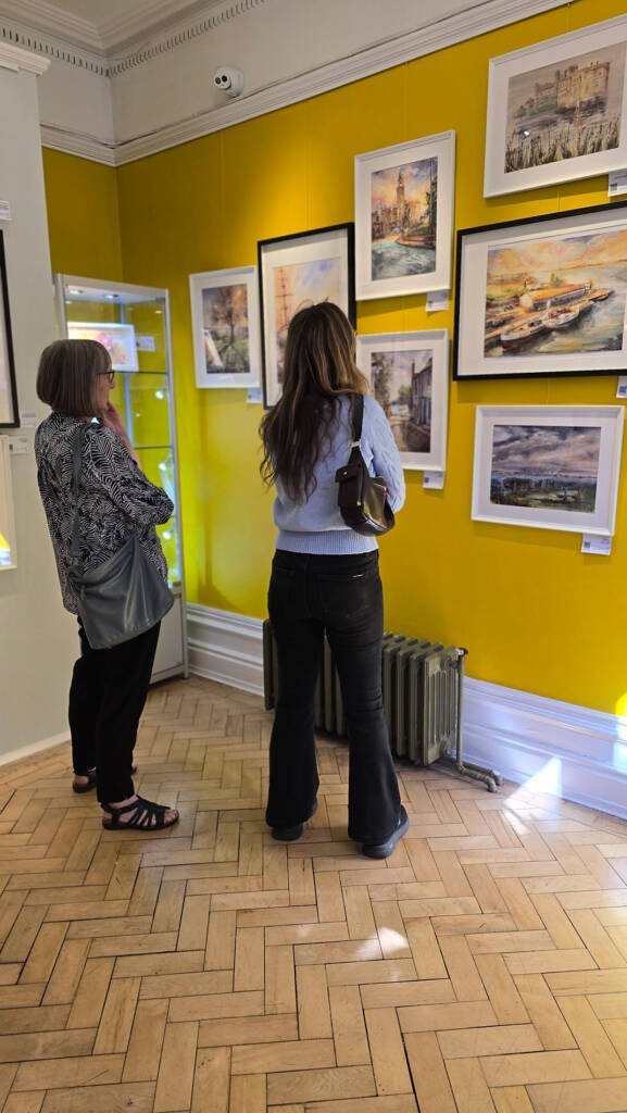 Visitors viewing original watercolour paintings by Aliya Bodnar at her solo exhibition in Rochester.